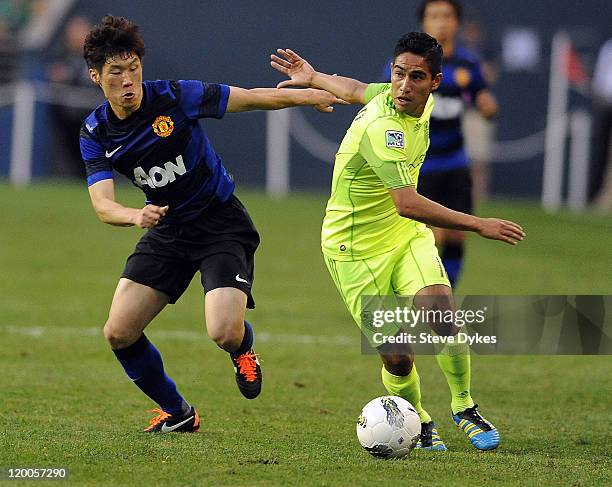 Ji-Sung Park of Manchester United battles for the ball with David Estrada of the Seattle Sounders FC during the second half of the game at...