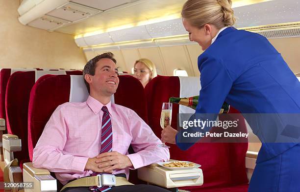 air hostess pouring champagne in first class - first class flight stock pictures, royalty-free photos & images