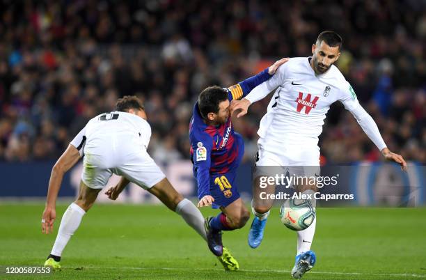 Lionel Messi of FC Barcelona is challenged by German Sanchez and Maxime Gonalons of Granada CF during the La Liga match between FC Barcelona and...