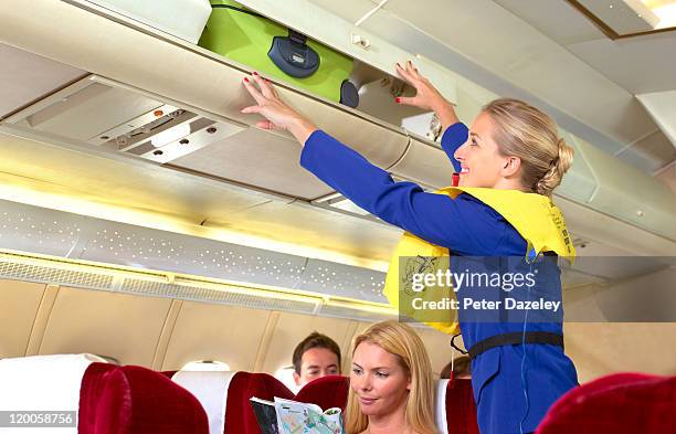 air hostess putting case in overhead locker - crew stock pictures, royalty-free photos & images