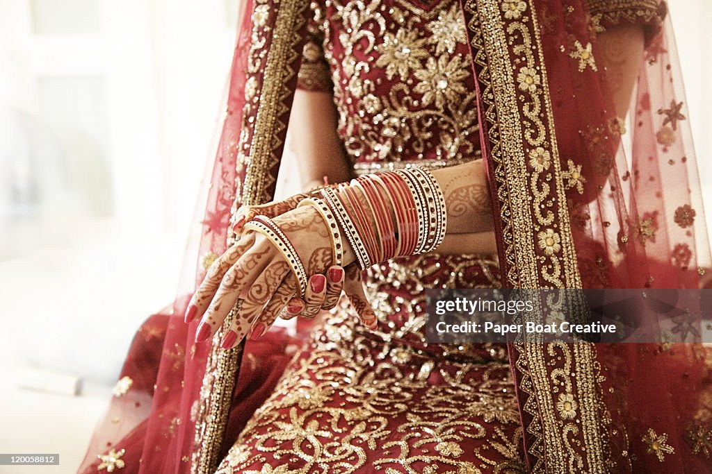 Bride putting on her red glass bracelets