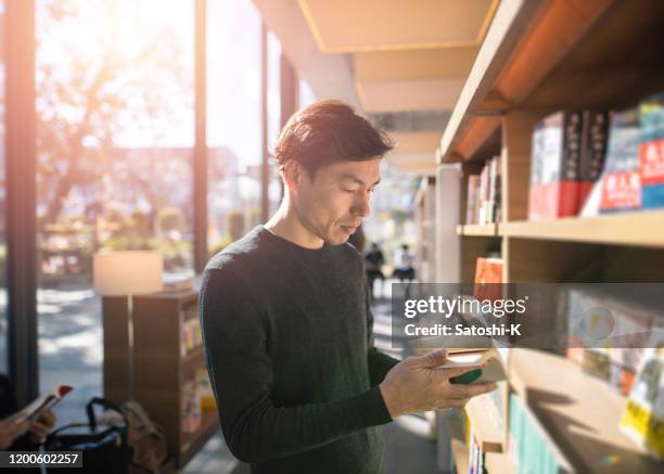 japanese man reading book at library - choosing a book stock pictures, royalty-free photos & images