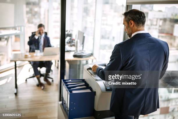 zakenman die afdrukt in het kantoor - faxmachine stockfoto's en -beelden