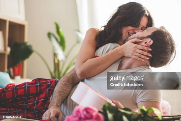 mulher que beija seu marido após o surpreender com um presente do dia do valentim - roupa de dormir - fotografias e filmes do acervo
