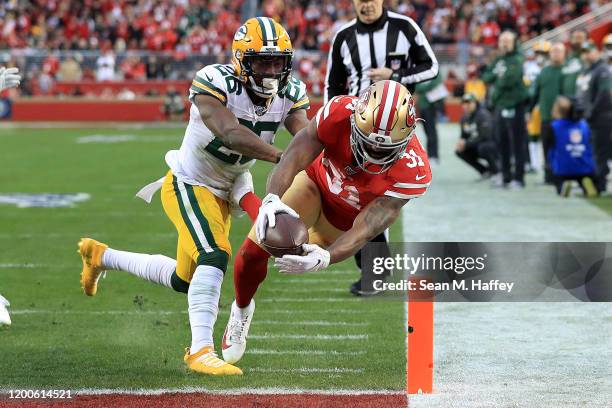 Raheem Mostert of the San Francisco 49ers dives into the end zone for a touchdown against Darnell Savage of the Green Bay Packers in the first half...