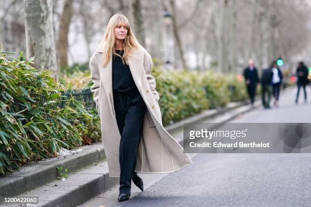 Jeanette Madsen wears a black top, a cream-color oversized wool coat, black pants, black pointy boots, outside Paul Smith, during Paris Fashion Week...