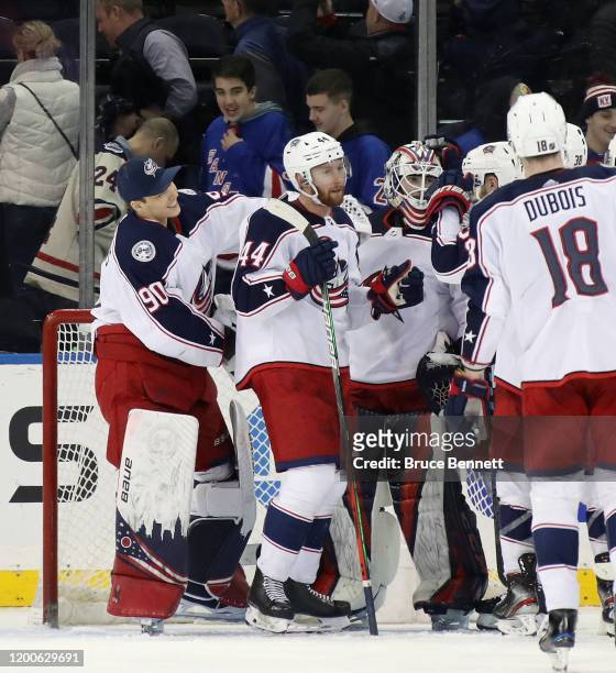 Fellow Latvia born goaltender Elvis Merzlikins of the Columbus Blue Jackets reaches in to congratulate Matiss Kivlenieks on his first NHL win in his...