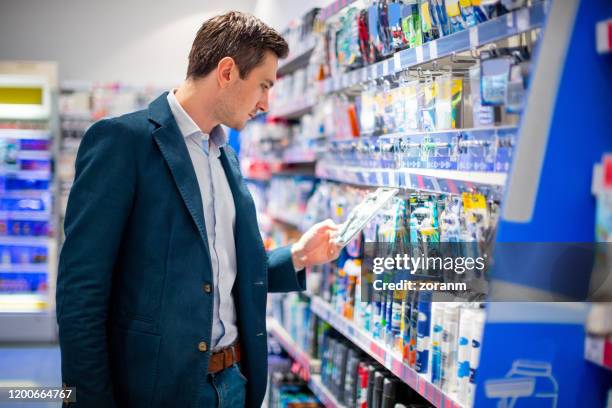 hombre comprando cosméticos en grandes almacenes - pasillo objeto fabricado fotografías e imágenes de stock