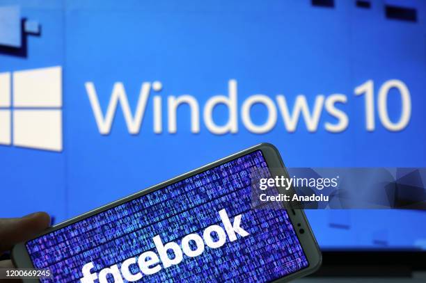 Phone screen displays Facebook logo with computer operating system 'Windows 10' in back of it, in Ankara, Turkey on February 13, 2020.