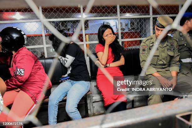 This picture taken on late February 13, 2020 shows a group of women detained during a raid at a hotel in Makassar, where they were caught in the...