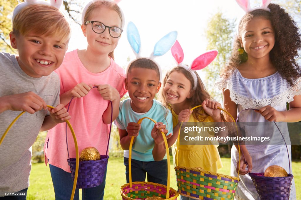 Portrait Of Five Children Wearing Bunny Ears On Easter Egg Hunt In Garden