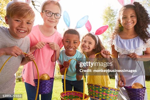 Portrait Of Five Children Wearing Bunny Ears On Easter Egg Hunt In Garden Portrait Of Five Children Wearing Bunny Ears On Easter Egg Hunt In Garden