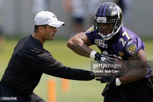 Head coach John Harbaugh hands the ball off to running back Ray Rice of the Baltimore Ravens during training camp on July 29, 2011 in Owings Mills,...