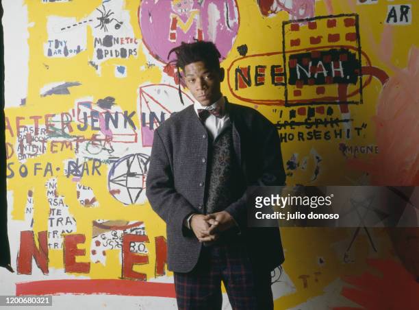 American artist, musician and producer of Haitian and Puerto Rican origins Jean-Michel Basquiat, in front of one of his paintings, during an...