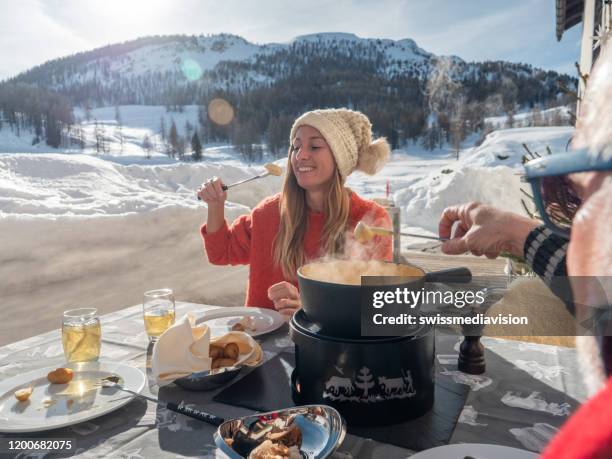 冬のアルプスでスイスのチーズフォンデュを食べる家族 - スイス文化 ストックフォトと画像