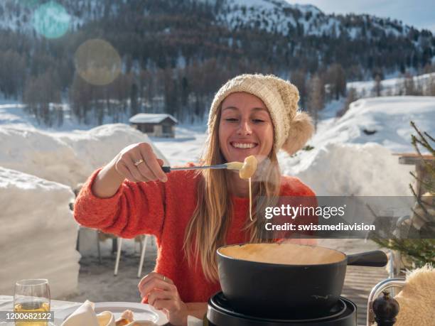 junge frau isst käsefondue in chalet - käse essen stock-fotos und bilder