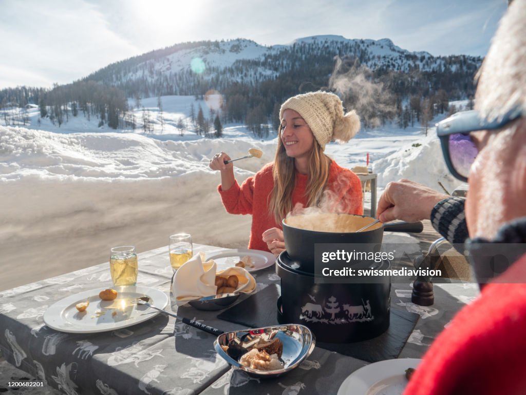 Familie isst Schweizer Käsefondue in den Alpen im Winter