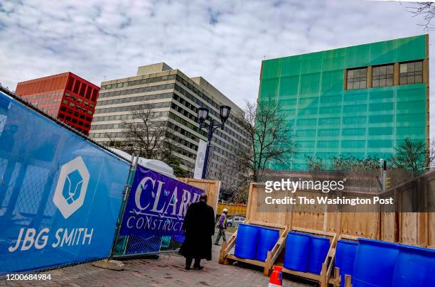 Pedestrian passes through a construction detour near sites -- including the buildings in the center and right -- that will be part of Amazon's...
