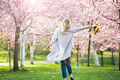 Dancing, running and whirling in beautiful park with cherry trees in bloom