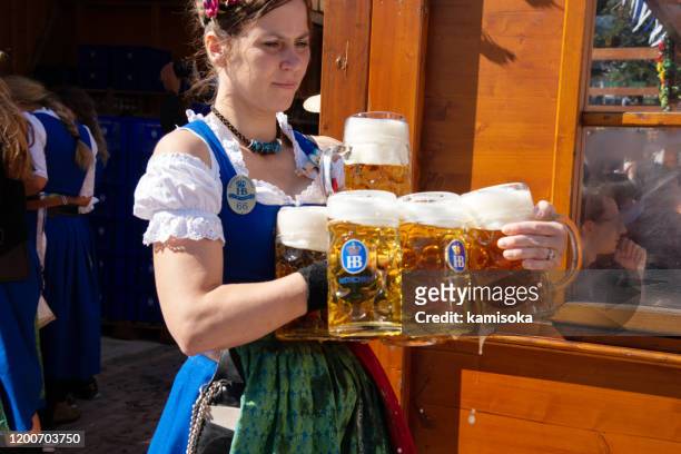 waitress carrying beer glasses at the oktoberfest in munich, germany - biergarten münchen stock pictures, royalty-free photos & images