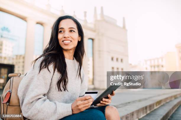 girl holding a credit card and a tablet - travel credit card stock pictures, royalty-free photos & images