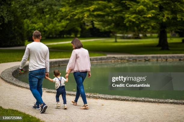 jeunes couples marchant avec leur fils par le lac dans la vieille ville européenne - castle square photos et images de collection