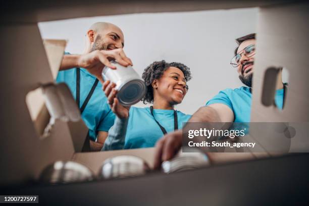 divers bénévoles emballant des boîtes de dons avec de la nourriture en conserve dans une banque alimentaire - reverse photos et images de collection