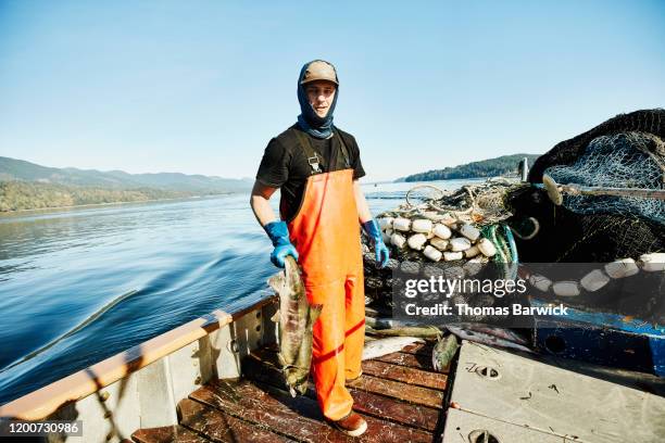 portrait of crew member of fishing boat holding chum salmon on deck of boat - fisherman stockfoto's en -beelden