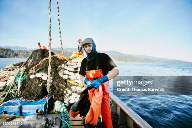 crew member of purse seiner taking off rain gear after hauling in net while fishing for salmon - fishing for leave stock-fotos und bilder