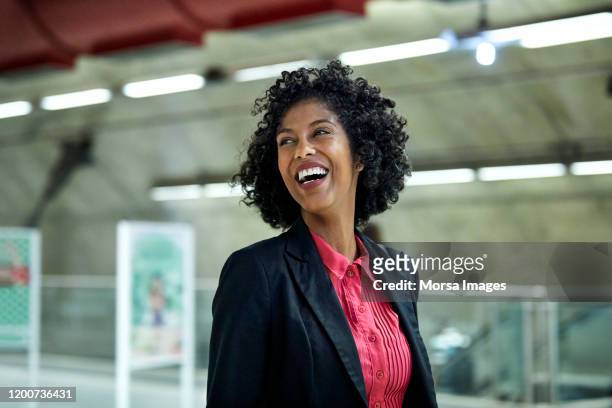 cheerful businesswoman looking away at station - black suit stockfoto's en -beelden