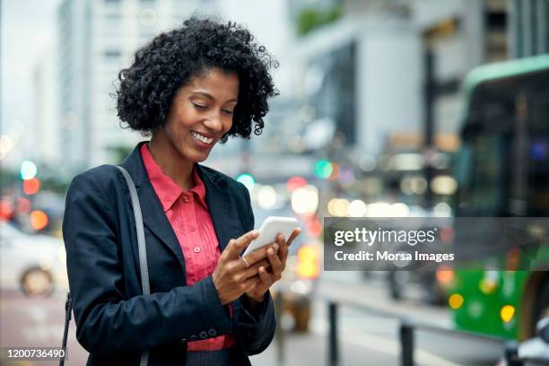smiling businesswoman surfing net on mobile phone - brazil city stock pictures, royalty-free photos & images