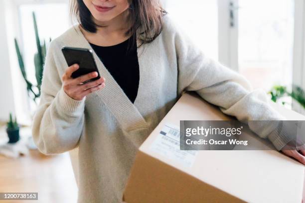 smiling woman receiving parcel at home - returning package stock pictures, royalty-free photos & images