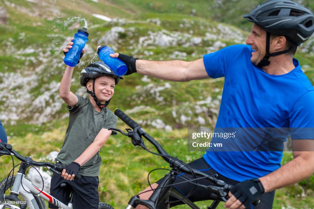 Father and son squirting water during a cycling water break