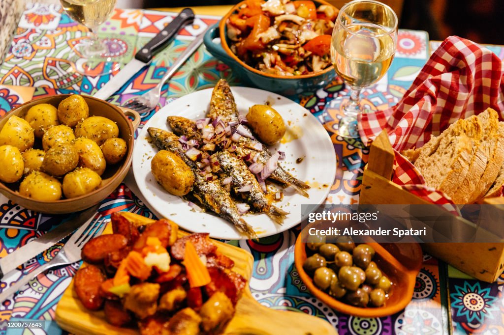 Traditional Portuguese dinner with grilled sardines, potatoes, olives, octopus salad and fresh bread, Lisbon, Portugal