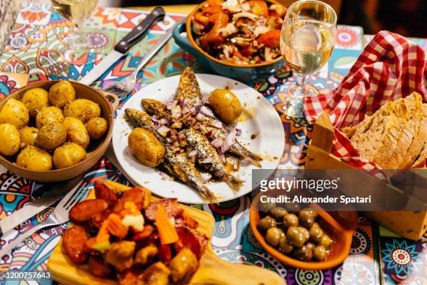 traditional portuguese dinner with grilled sardines, potatoes, olives, octopus salad and fresh bread, lisbon, portugal - cultura portoghese foto e immagini stock