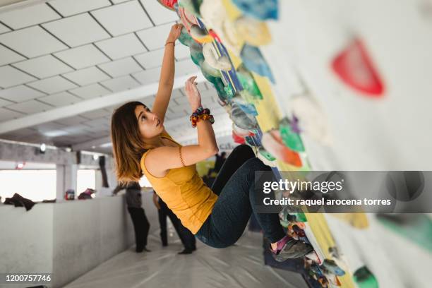 female climber clinging to indoor climbing wall - boulderen stockfoto's en -beelden