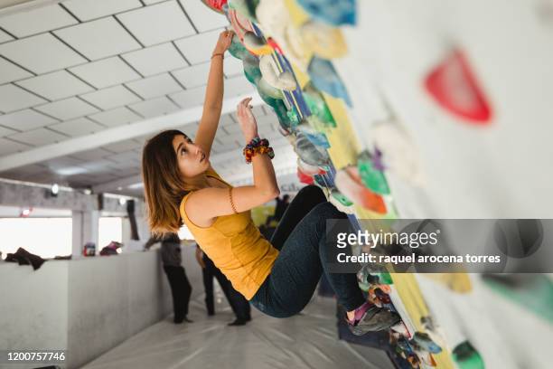 female climber clinging to indoor climbing wall - bouldering - fotografias e filmes do acervo