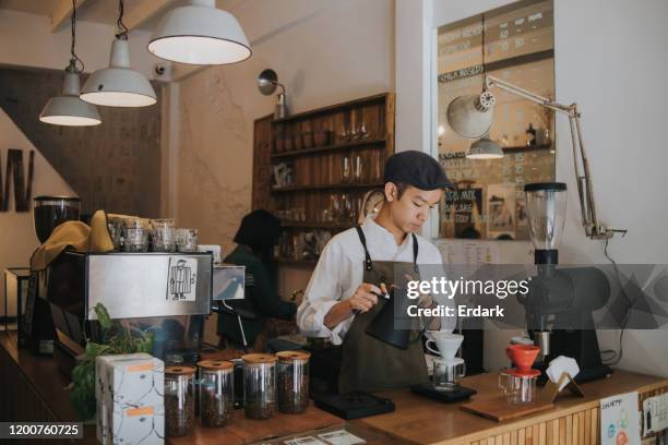 concentration of asian hipster barista adding hot water into coffee dripper above glass jar - barista stock pictures, royalty-free photos & images