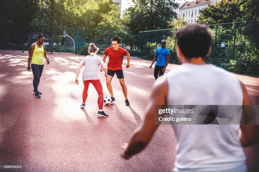 Young sportsmen and woman playing soccer on hardcourt