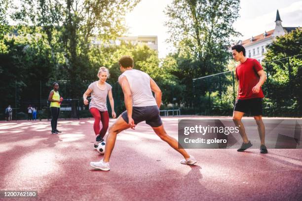 junge sportler und frauen, die auf dem hartplatz fußball spielen - mixed age range stock-fotos und bilder