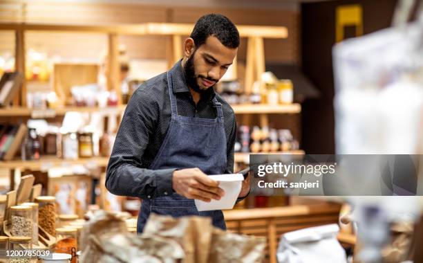 employee working at the bio grocery shop - groceries tablet stock pictures, royalty-free photos & images