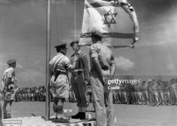 Picture released 08 June 1948 shows an Israeli officer raising the National Flag for the first time during the celebration of the birth of the...