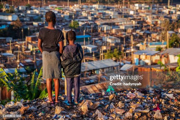 african little girls standing in trash and looking at kibera slum, kenya, east africa - slum africa stock pictures, royalty-free photos & images