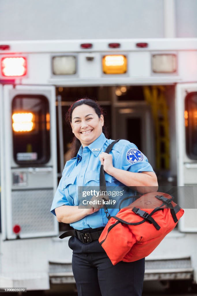 Female paramedic standing at the rear doors of an ambulance