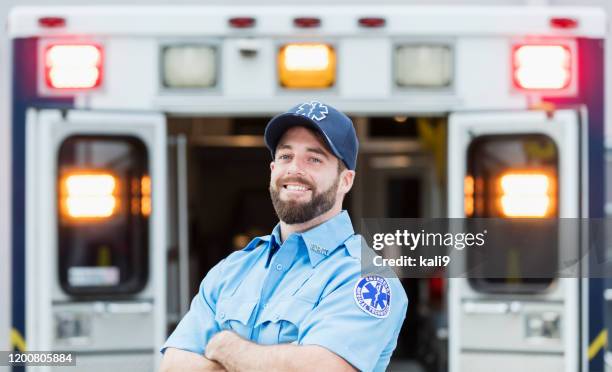 paramedic standing at the rear doors of an ambulance - paramedic stock pictures, royalty-free photos & images