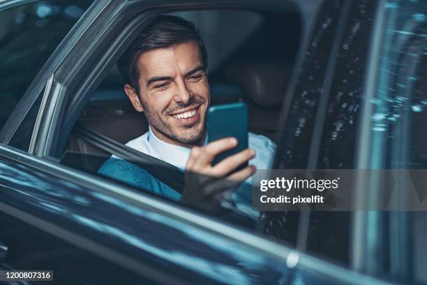 businessman with a cell phone on the back seat of a car - management car smartphone stock pictures, royalty-free photos & images