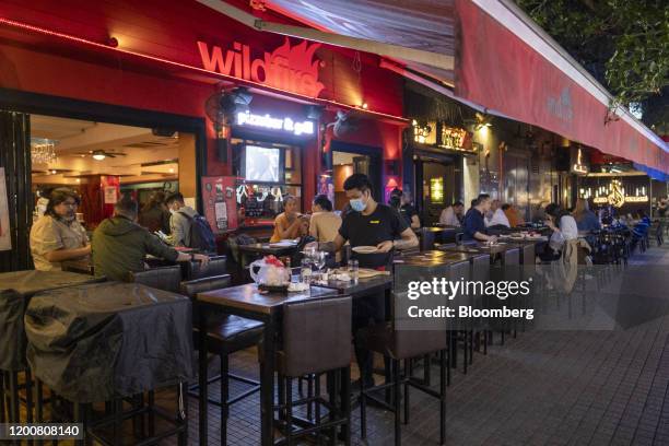 An employee wearing a protective mask cleans a table at a Wildfire restaurant at Knutsford Terrace at night in the Tsim Sha Tsui district of Hong...