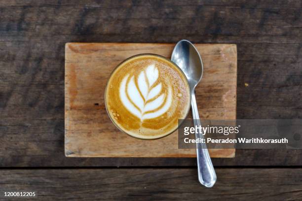 top flat view view at one cup of cappuccino or latte with flower pattern of latte art in transparent glass on wooden tray and table. hipster vibes and vintage tone. - coffee cup top view stockfoto's en -beelden