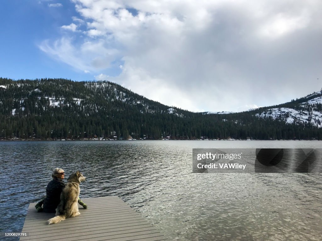 Grandmother and Siberian husky sit on a dock on Donner Lake.