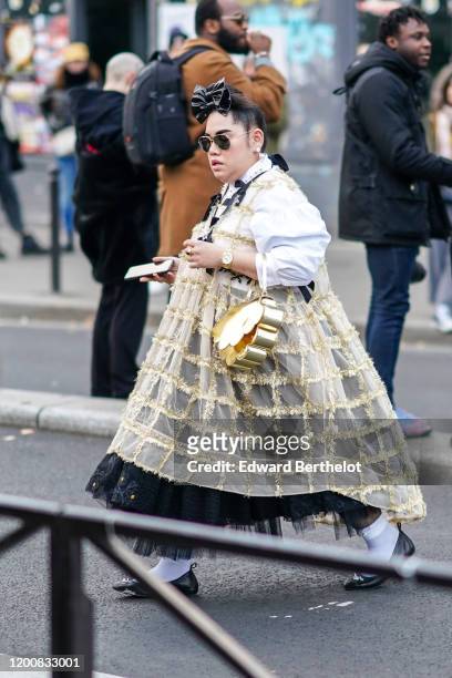 Guest wears a double bow in the hair, sunglasses, earrings, a ring, a see-through light yellow check jumper with glittering gold-tone threads, a...
